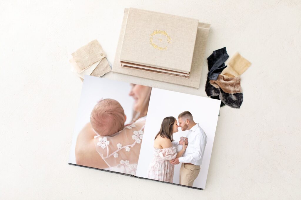 An album laying open on a table showcasing two beautiful newborn images. Above the different cover materials in velvet and linen are shown. 