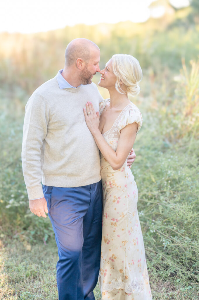 A beautiful portrait of a husband and wife embracing and smiling at each other in the light of the sun setting behind them. 